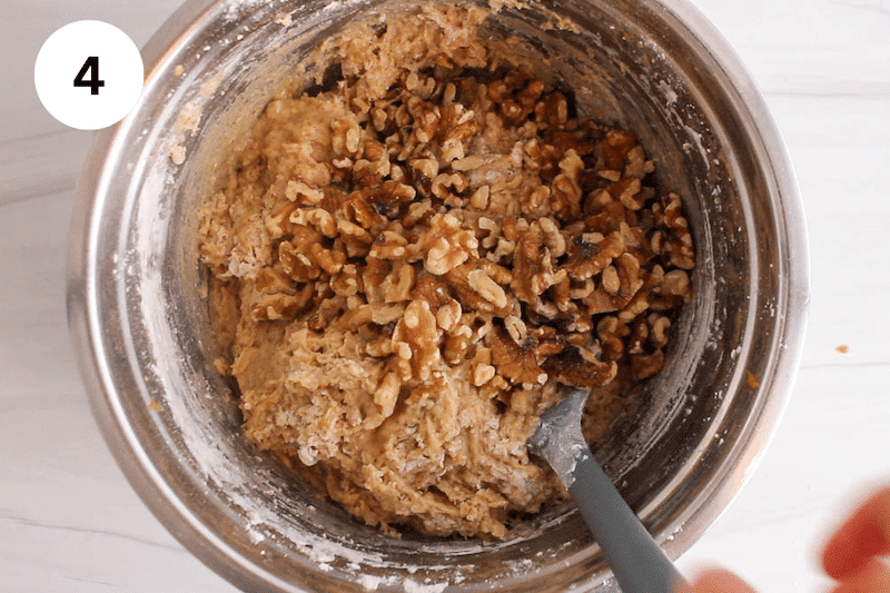 A bowl with a banana bread batter topped with walnuts.