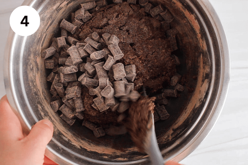 A mixing bowl with a spatula and a brownies batter topped with chocolate chips.