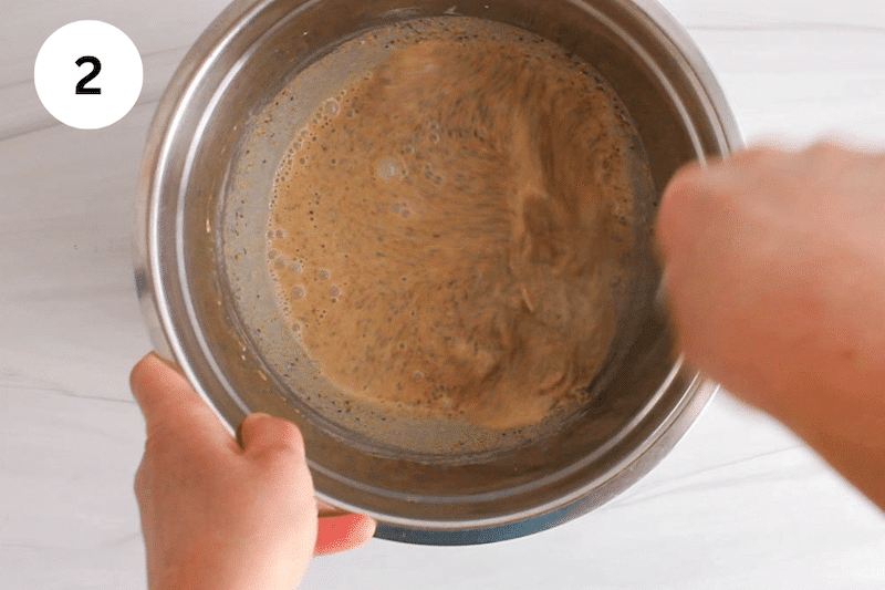 A large whisk mixing in a bowl with almond butter and wet ingredients.