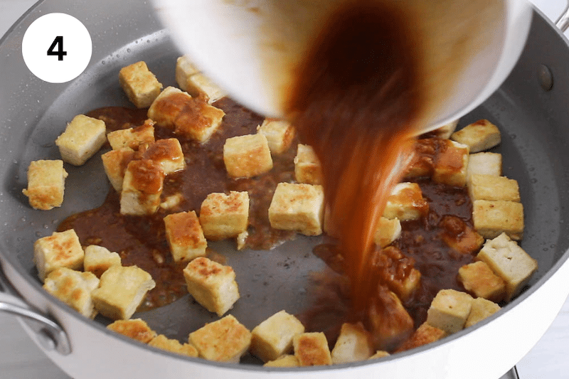 A bowl pouring a ginger garlic sauce over a pan with fried tofu.