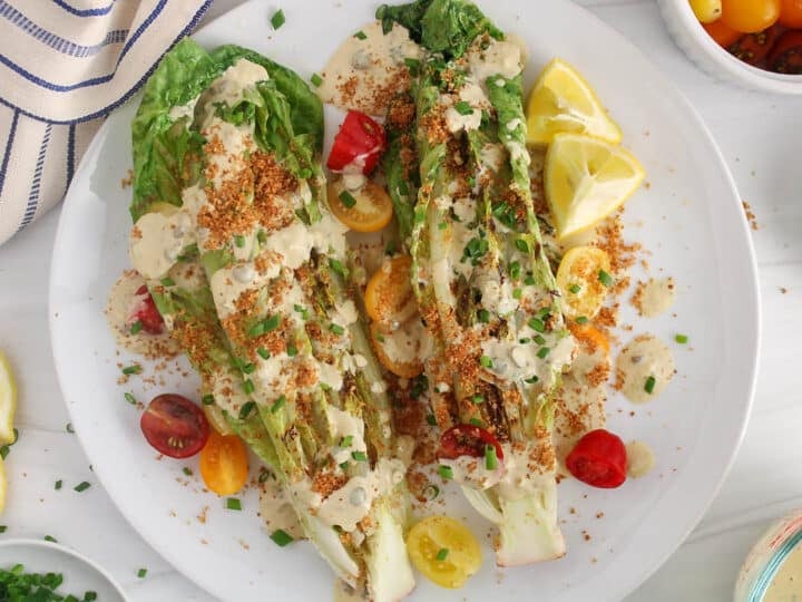 Wedges of grilled romaine hearts garnished with tahini cesar dressing, breadcrumbs and cherry tomatoes.