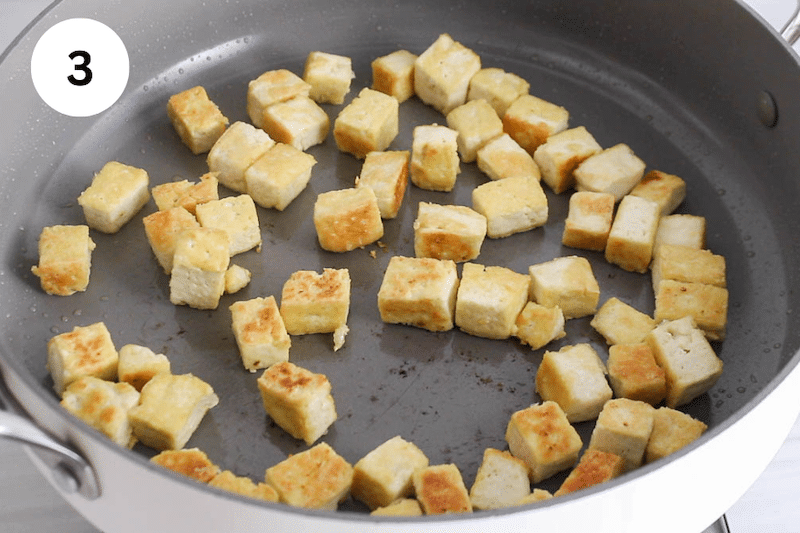 A pan frying some cubes of tofu.