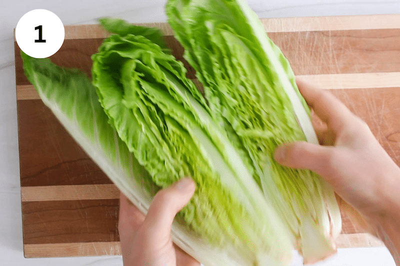 Hands dividing 2 halves of a heart of Romaine.