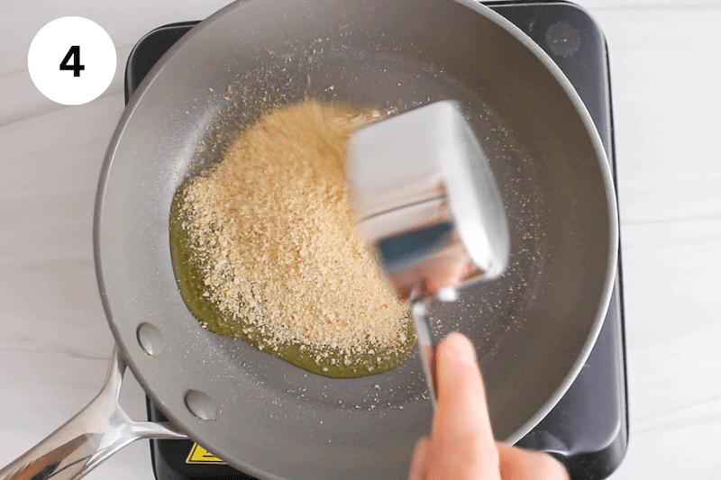 Breadcrumbs added to a pan with oil.