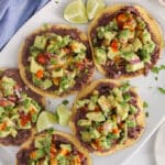 A platter of avocado tostadas with a drizzle of hot sauce.