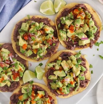 A platter of avocado tostadas with a drizzle of hot sauce.