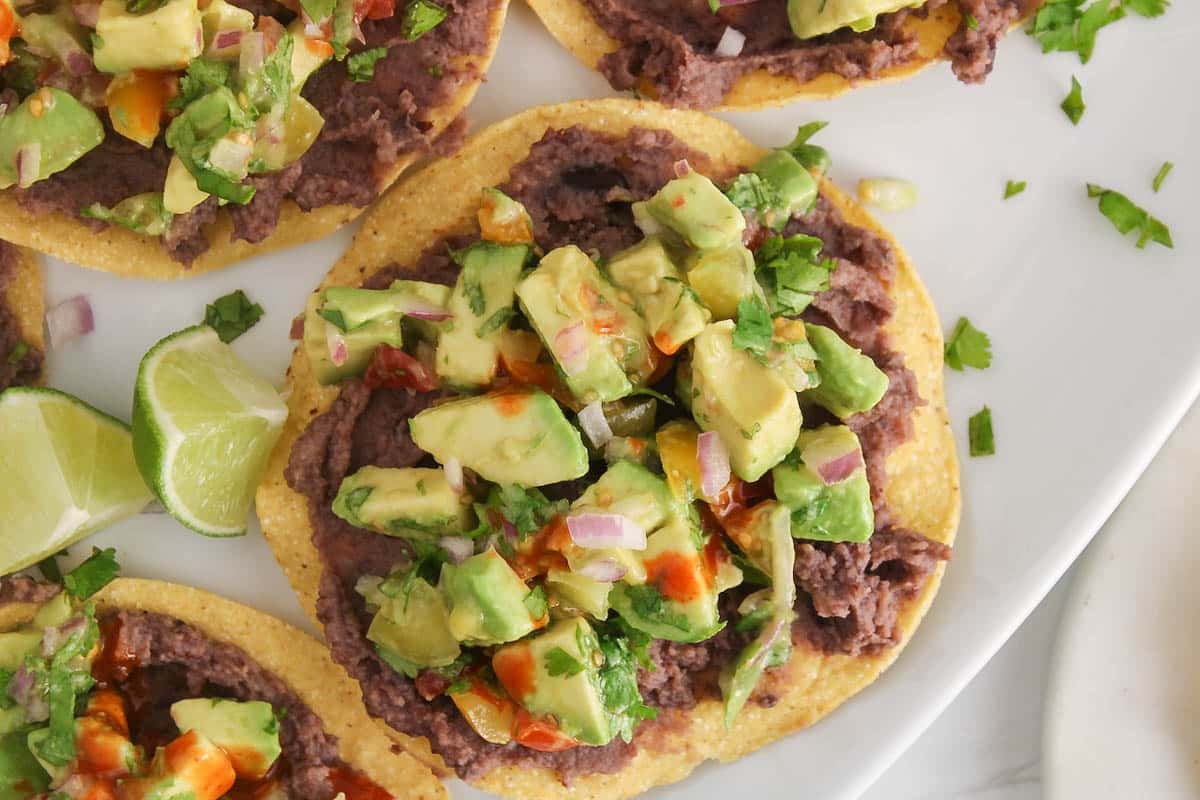 Avocado tostadas covered with cilantro and red onion.