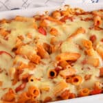 White baking dish with rigatoni noodle in marinara sauce topped with Alfredo sauce.