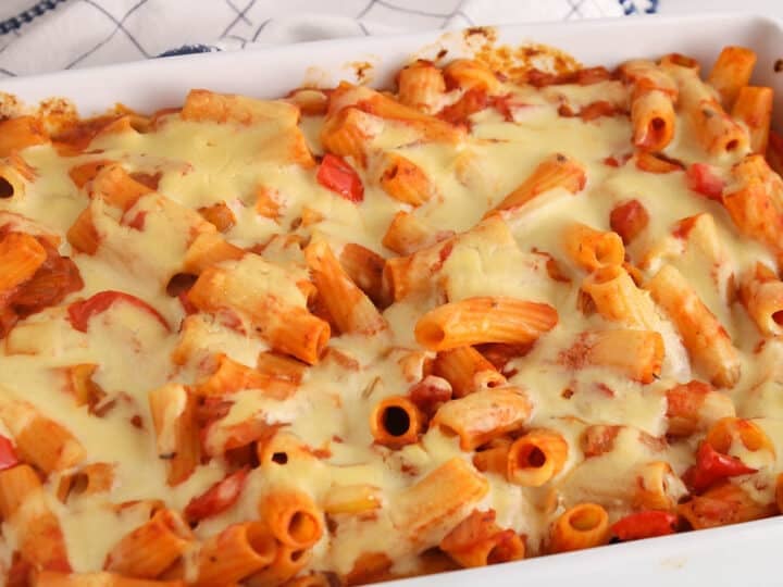 White baking dish with rigatoni noodle in marinara sauce topped with Alfredo sauce.