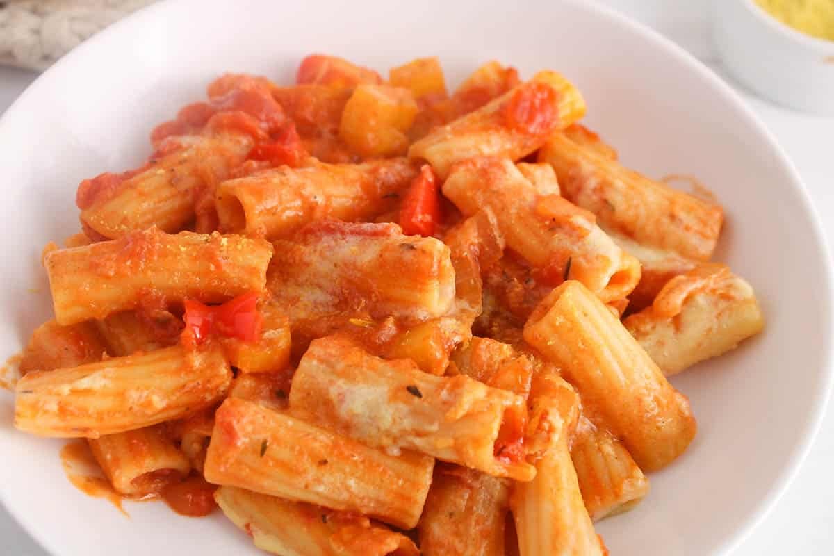 Serving white plate with marinara pasta and Alfredo sauce.