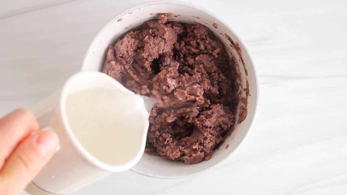 There a small jar pouring water over refried beans.