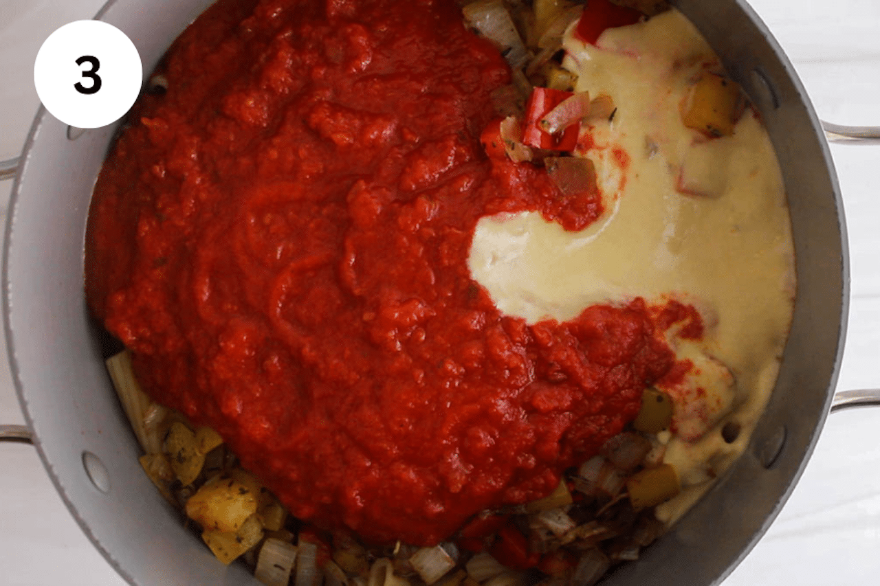 A large pot with pasta and marinara sauce with Alfredo sauce.