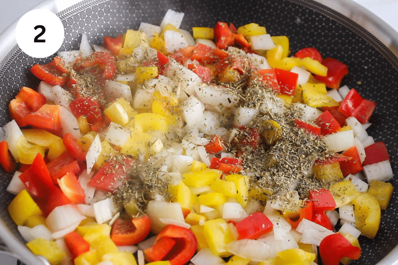 A pan cooking onion with peppers and spices.