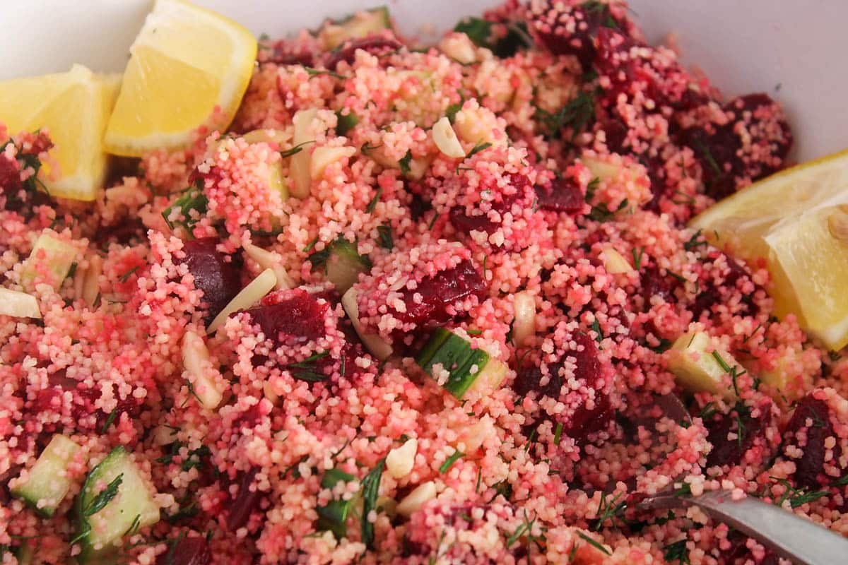 Beet couscous salad with cucumber and dill and lemon wedges.