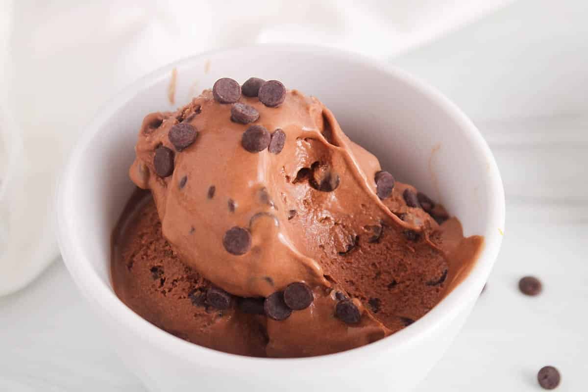 A bowl of vegan chocolate ice cream with a bite taken off.
