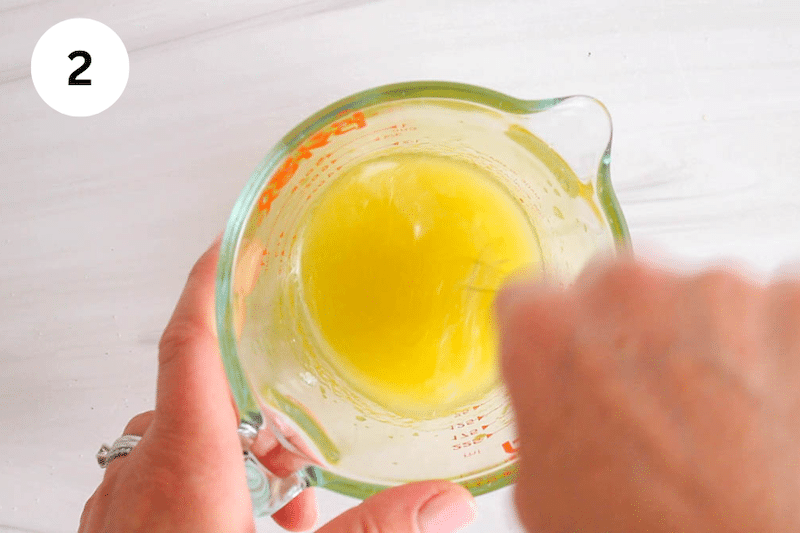 A small jar with a hand whisking a dressing.