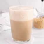 Large glass of oat milk brown sugar latte with a bowl of brown sugar in the background.
