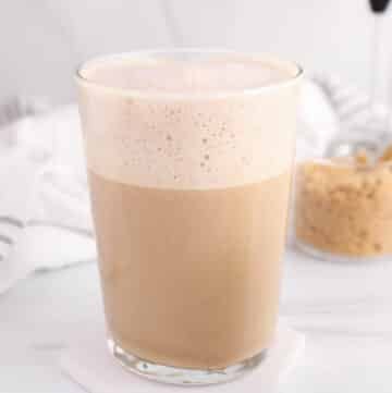 Large glass of oat milk brown sugar latte with a bowl of brown sugar in the background.