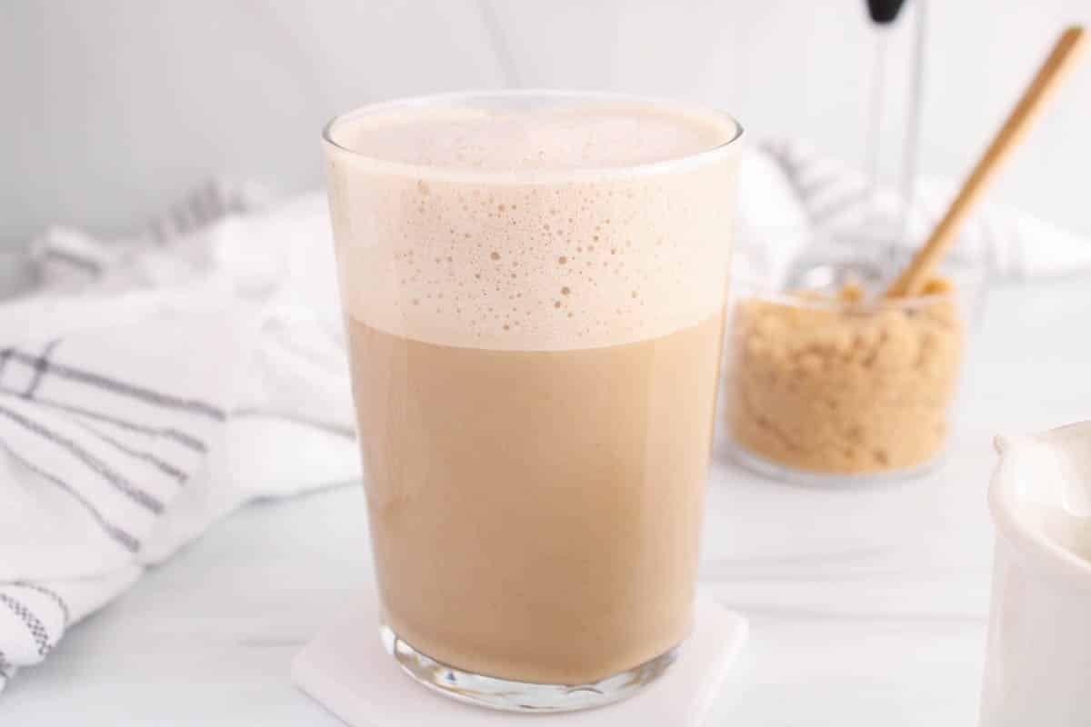 Large glass of oat milk brown sugar latte with a bowl of brown sugar in the background.