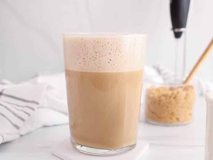 Large glass of oat milk brown sugar latte with a bowl of brown sugar in the background.