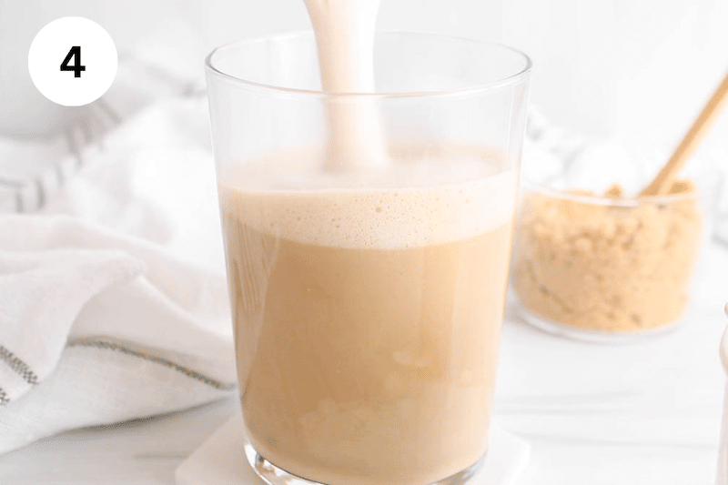 Milk pouring over coffee in a large glass.