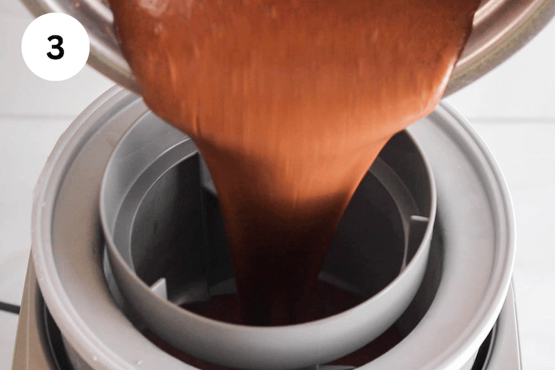 A chocolate milk mixture pouring into an ice cream machine.