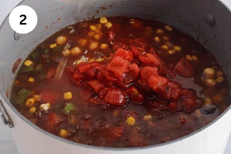 A large pot of soup with tomatoes simmering.