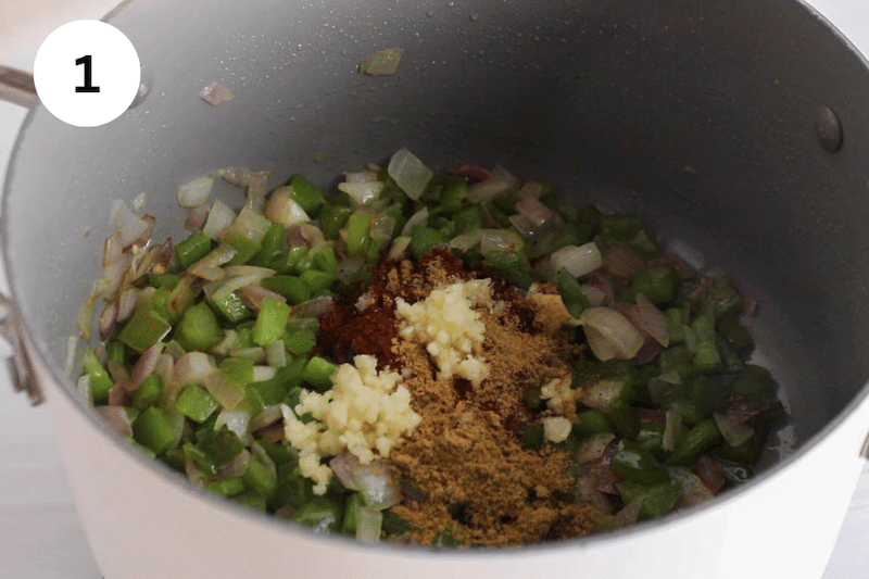 A large pot cooking onion, pepper and aromatics.