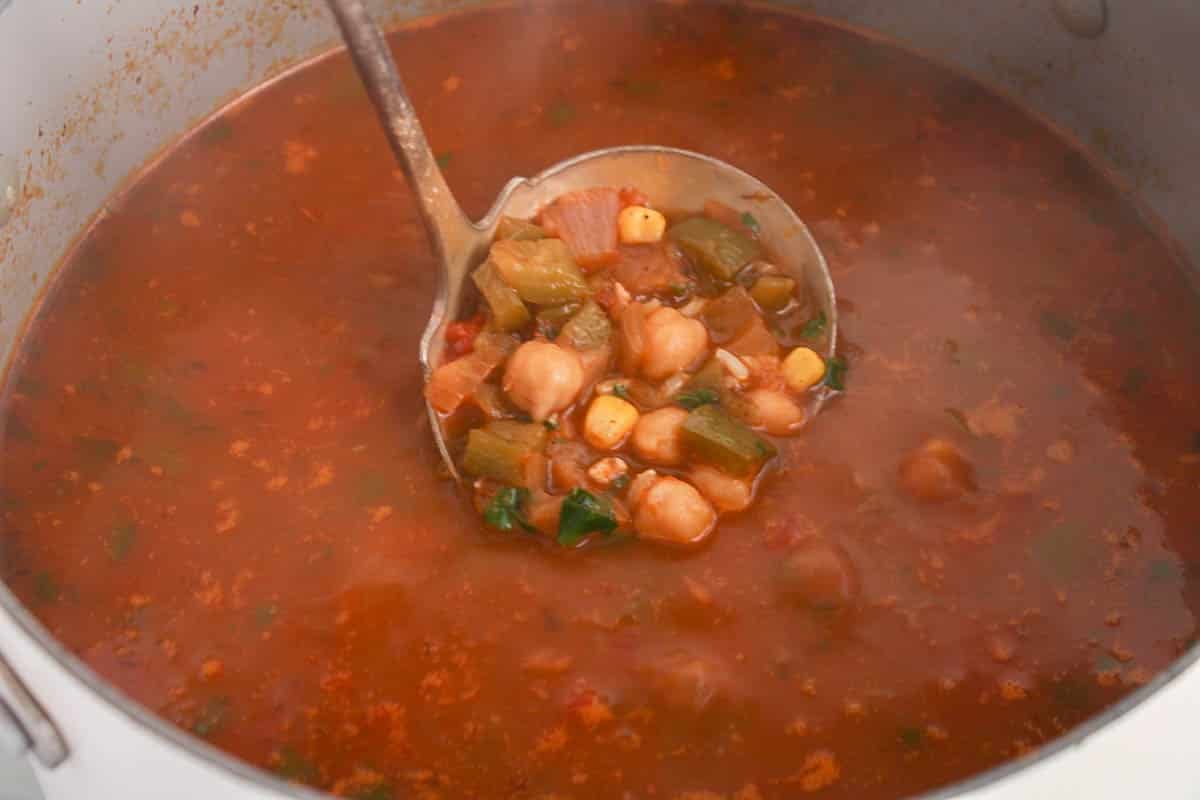 A ladle taking some Mexican chickpea taco soup from a large pot.