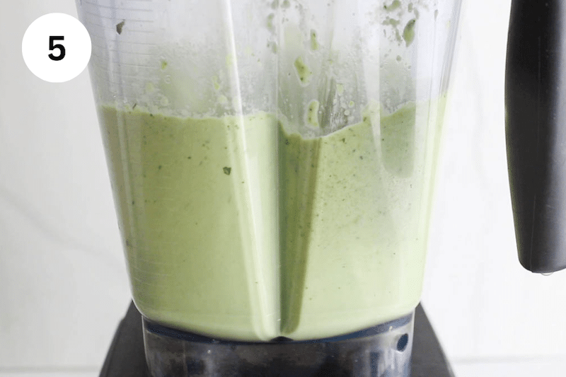 A blender with a creamy light green sauce.