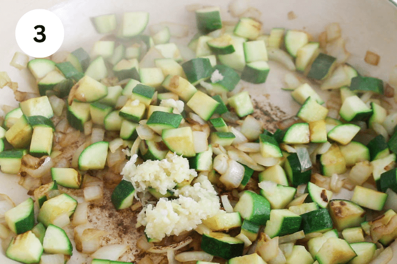 A large pan cooking onion with zucchini.